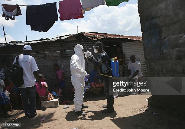 Health workers suit up in protective clothing , before taking people suspected of having Ebola to a re-opened Ebola holding center in the West Point...