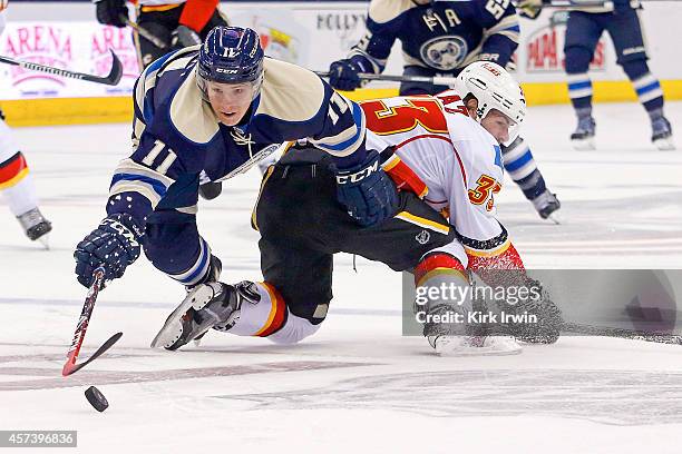 Matt Calvert of the Columbus Blue Jackets dives over Rapheal Diaz of the Calgary Flames in an effort to gain control of the puck during the second...