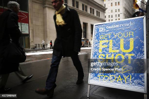 People walk past a sign advertising flu shots during a morning snow storm on December 17, 2013 in New York City. The metro area is expecting another...