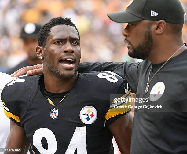 Wide receiver Antonio Brown of the Pittsburgh Steelers talks to head coach Mike Tomlin as they leave the field after the first half of a game against...