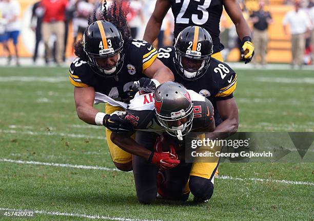 Wide receiver Louis Murphy of the Tampa Bay Buccaneers is tackled by safety Troy Polamalu and cornerback Cortez Allen of the Pittsburgh Steelers...