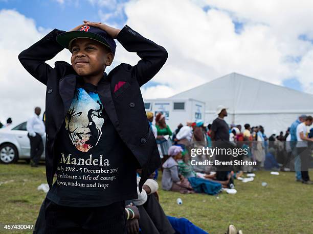 Young boy in a Nelson Mandela T Shirt watches Mandela's funeral on a jumbo television broadcasting the service taking place in the valley below,...