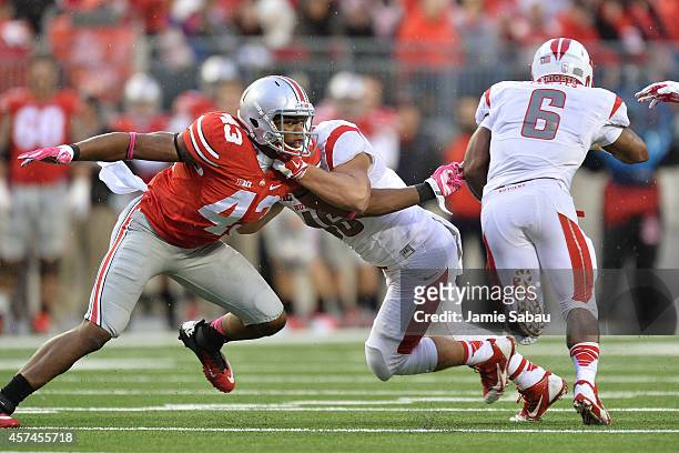 Darron Lee of the Ohio State Buckeyes reaches out to try and stop ballcarrier Desmon Peoples of the Rutgers Scarlet Knights in the third quarter on...