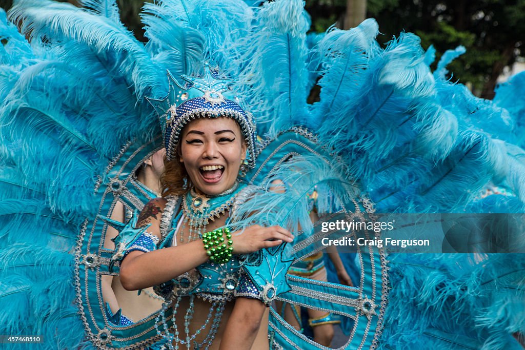 A feathered dancer laughs during an arts festival. The Dream...