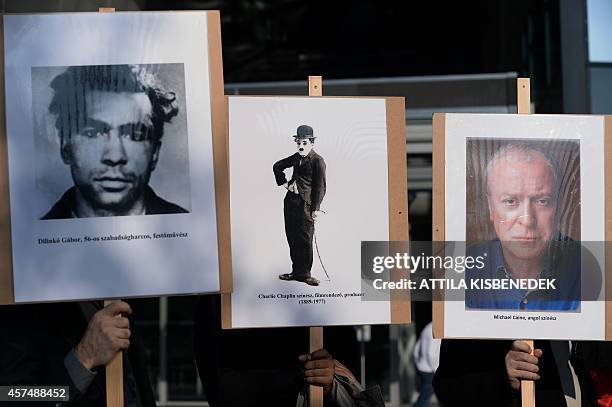 Demonstrators hold placards depicting the 1956 revolution victim Hungarian Gabor Dilinko, British comedian and director Charlie Chaplin and British...