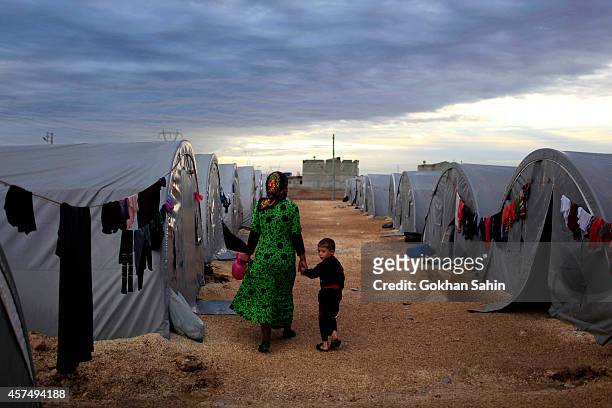 Kurdish refugee mother and son from the Syrian town of Kobani walk beside their tent in a camp in the southeastern town of Suruc on the...
