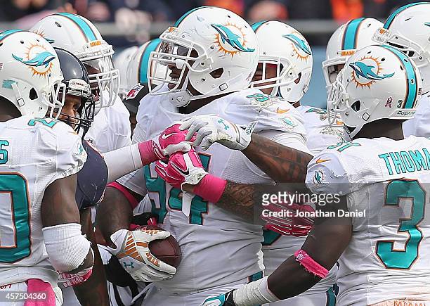 Randy Starks of the Miami Dolphins smiles as he is surrounded by teammates after recovering a Chicago Bear fumble at Soldier Field on October 19,...