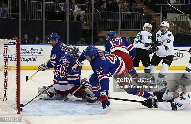 Matt Hunwick of the New York Rangers reaches to stop the puck from crossing the goal line as Logan Couture of the San Jose Sharks hits the ice during...