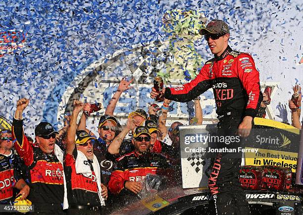 Brad Keselowski, driver of the Redd's Wicked Apple Ale Ford, celebrates in victory lane after winning the NASCAR Sprint Cup Series GEICO 500 at...