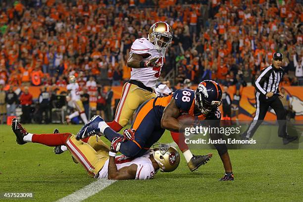 Wide receiver Demaryius Thomas of the Denver Broncos crashes over the goal line for a third quarter touchdown reception under coverage by cornerback...