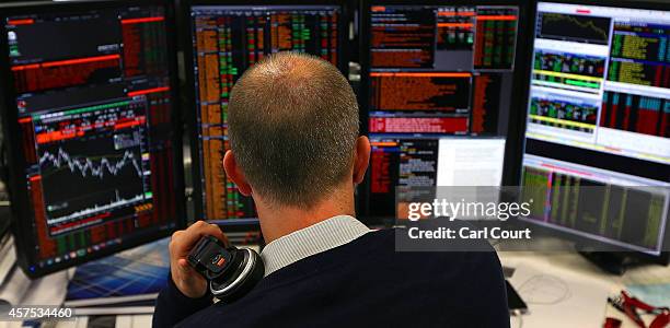 An employee views trading screens at the offices of Panmure Gordon and Co on October 20, 2014 in London, England. Markets stabilised over the weekend...