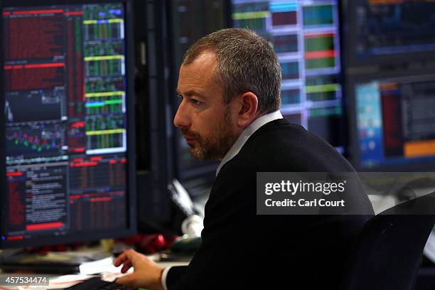 An employee views trading screens at the offices of Panmure Gordon and Co on October 20, 2014 in London, England. Markets stabilised over the weekend...