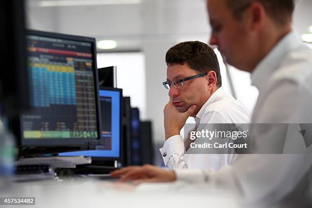 An employee views trading screens at the offices of Panmure Gordon and Co on October 20, 2014 in London, England. Markets stabilised over the weekend...