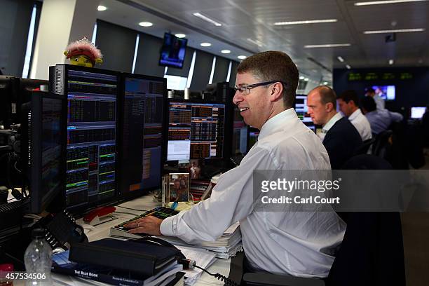 An employee views trading screens at the offices of Panmure Gordon and Co on October 20, 2014 in London, England. Markets stabilised over the weekend...