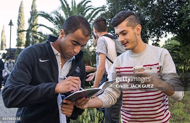 Paris Saint-Germain's midfielder Lucas gives an autograph as he arrives at a hotel in the Cypriot capital Nicosia on the eve of the UEFA Champions...