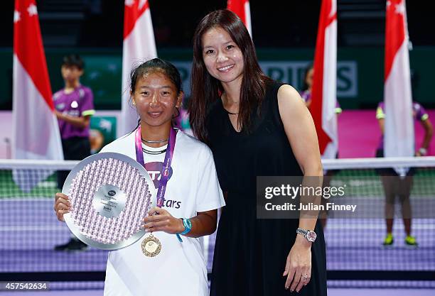 Thasaporn Naklo of Thailand with the winners trophy next to Li Na of China after defeating Yuki Ando of Japan in the U14 Future Stars final during...