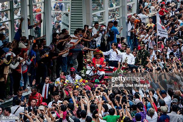 Indonesian President Joko Widodo and Vice President Jusuf Kalla wave to the crowd while on his journey to Presidential Palace by carriage during the...