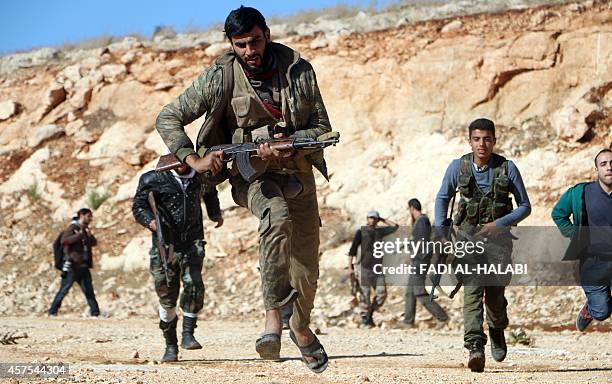 Rebel fighters run during a battle against Syrian government soldiers in Handarat, on the northern outskirts of Aleppo, on October 20, 2014. Syrian...