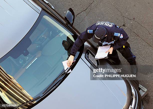 Policeman issues on December 18, 2013 a parking ticket on a car which was parked in front of a garage in Lille, before it was to be loaded onto a tow...