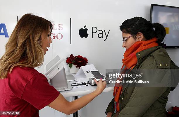 Worker demonstrates Apple Pay inside a mobile kiosk sponsored by Visa and Wells Fargo to demonstrate the new Apple Pay mobile payment system on...