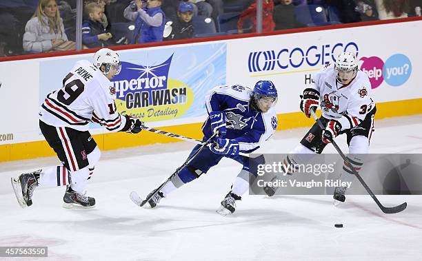 Cody Payne and Brian Brosnan of the Niagara Ice Dogs battles for the puck with Danny Desrochers of the Sudbury Wolves in an OHL game between the...