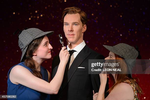 Fans Daisy England and Charlie Mitchell pose with Sherlock Holmes-style deerstalker hats and a magnifying glass around the new wax figure of British...