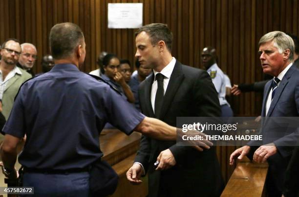 South African Paralympic athlete Oscar Pistorius is lead by officer into a holding cell after being sentenced at the high court in Pretoria, on...