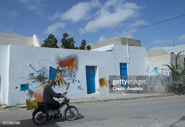 Man is seen in front of a wall with a three dimensional picture in Djerba island of Tunisia, on October 17, 2014. Three dimensional pictures painted...