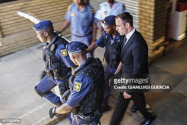 South African Paralympian athlete Oscar Pistorius is escorted by south african policemen to a police vehicle to transported to prison at the High...