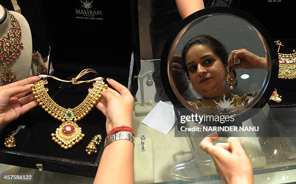 Indian shoppers try on gold jewellery at a jewellery store on Dhanteras in Amritsar on October 21, 2014. Dhanteras, which happens two days before the...