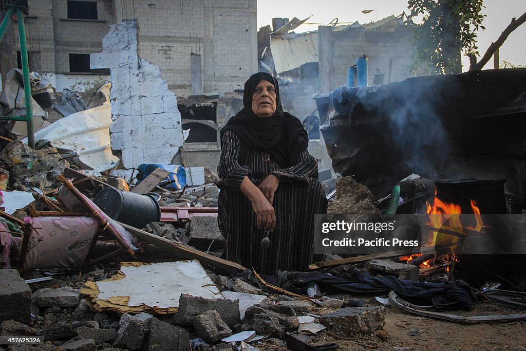 A Palestinian woman cooking breakfast over a house rubbles...