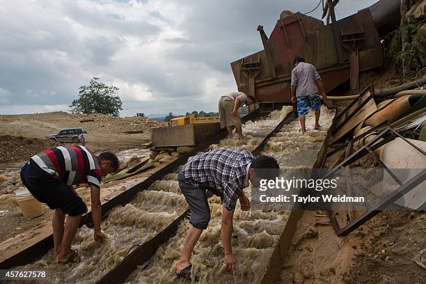Chinese gold miners remove grates from a large waterway used to separate and trap the heavier gold from the soil at a gold mining site near Laiza,...