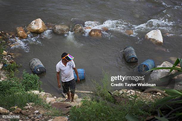 Chinese gold miner walks past a river where barrels of oil have been deposited at a gold mining site near Laiza, Kachin State, Myanmar. In...