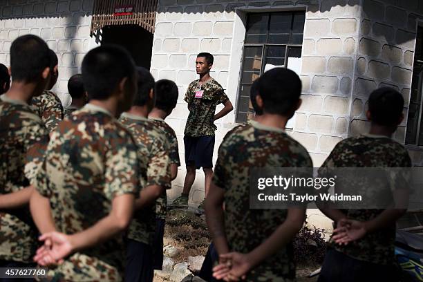 Recruits wait at attention as cleaning assignments are given out at a training camp in Laiza, Kachin State, Myanmar. The Kachin Independence Army is...