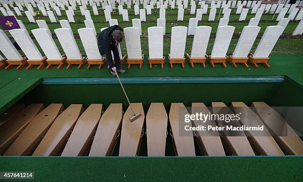 Worker clears leaves from coffins containing the remains of 15 British World War One soldiers at the Commonwealth War Graves Commission Y-Farm...