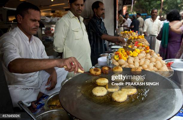 An Indian snacks vendor cooks aloo-tikki at a roadside shop in New Delhi on October 22, 2014. AFP PHOTO / PRAKASH SINGH
