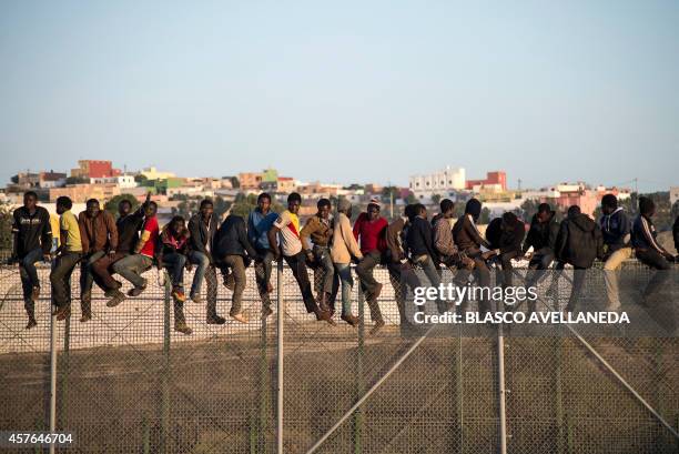 Would-be immigrants stand atop a boarder fence separating Morocco from the north African Spanish enclave of Melilla on October 22 following a morning...