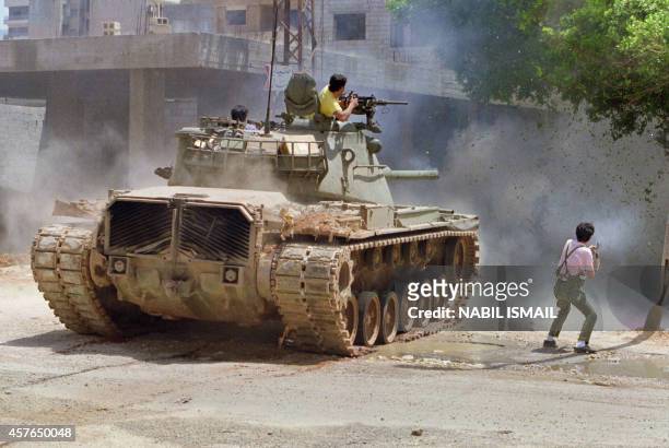 Militiamen from Amal, the first political organization of Lebanon's Shi'ite Moslems, fire from a tank 07 May 1988 in the Shi'ite southern suburb of...