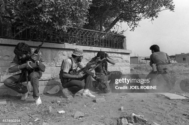 Three members of the pro-Syrian Amal militia, the first political organization of Lebanon's Shi'ite Muslims, take cover as their comrade opens fire...