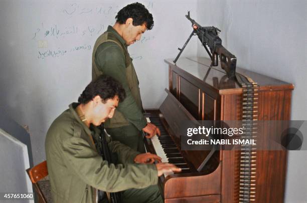 Two Muslim militiamen play piano 26 April 1985 in Saida during a break in the battle with the rebel Christian militia of the Lebanese Forces . At the...