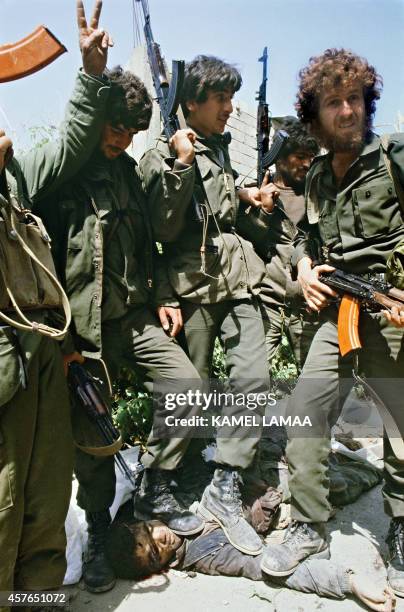 Druze militiamen of the pro-Syrian Progessive Socialist Party, backed by Palestinians, stand on a body of a dead Christian militiaman of the Lebanese...