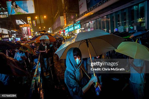 Pro-democracy protester watches police during heavy rain in Mong Kok on October 22, 2014 in Hong Kong. Police have begun to take measures to remove...