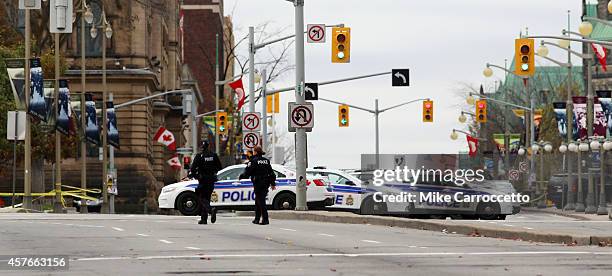 Ottawa police officers stand guard near the National War Memorial where a soldier was shot earlier in the day, just blocks away from Parliament Hill,...