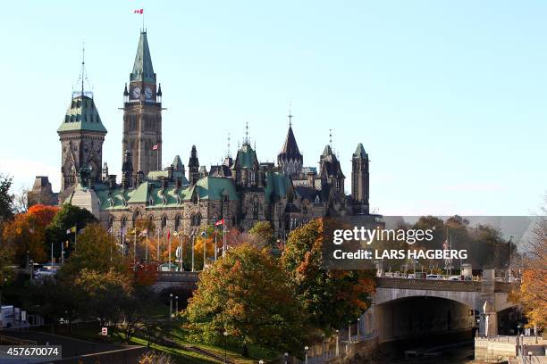 The Canadian flag flies over the Parliament hill in Ottawa, Canada on October 22, 2014. A gun man opened fire at the National War Memorial and killed...