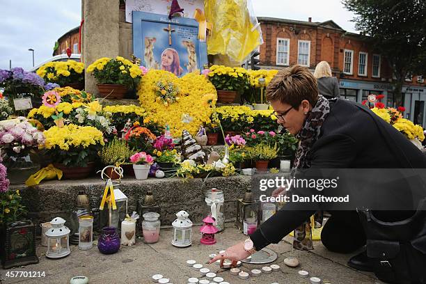 Members of the community light candles and place them besides the clock tower in Hanwell ahead of the funeral for murdered teenager Alice Gross on...