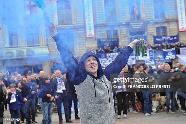 An Everton supporter holds a blue burning flare as others stand behind him after gathering on the Grand Place, the main square of the northern French...