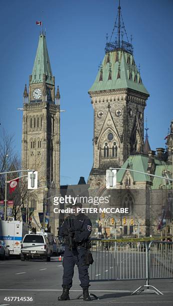 Heavily armed police officer stands watch in front of Parliament on October 23 near the National War Memorial in Ottawa, Ontario the day after...
