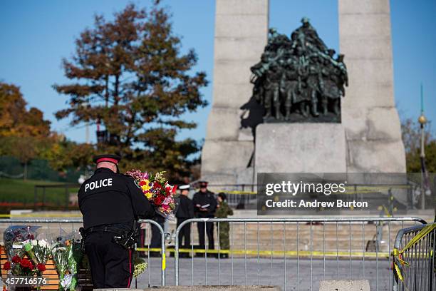 An Ottawa police officer lays flowers and pays his respects for Cpl. Nathan Cirillo of the Canadian Army Reserves at the National War Memorial, who...