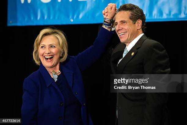 Former U.S. Secretary of State and U.S. Sen. Hillary Rodham Clinton raises the hand of incumbent New York Governor Andrew Cuomo laugh during a "Women...