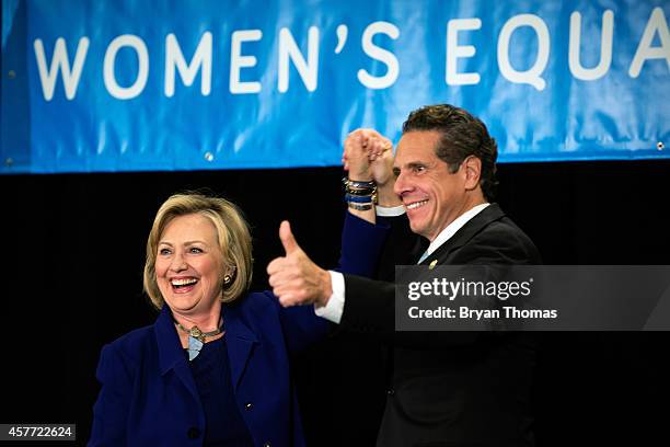 Former U.S. Secretary of State and U.S. Sen. Hillary Rodham Clinton raises the hand of incumbent New York Governor Andrew Cuomo laugh during a "Women...